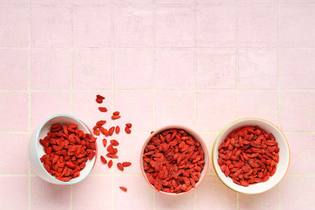 Bowl with red dried goji berries on pink tile backgroundの写真素材