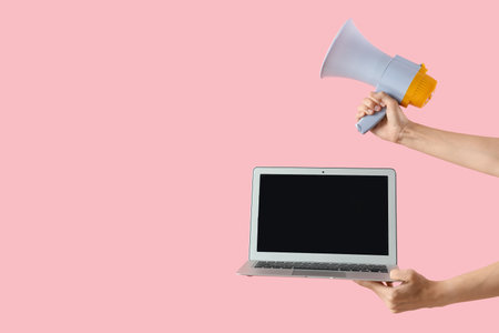Woman with blank laptop and megaphone on pink backgroundの写真素材