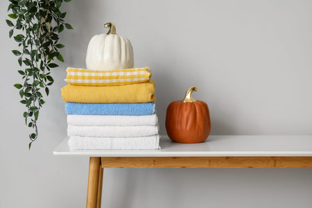 Stack of clean towels and decor on table near light wallの写真素材