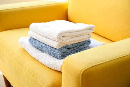 Stack of clean towels on colorful armchair, closeupの写真素材