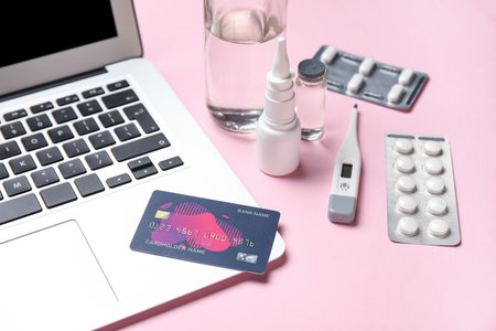 Laptop, credit card and items from first aid kit on pink backgroundの写真素材