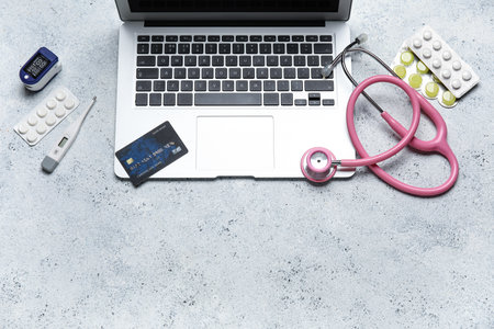 Laptop, credit card and items from first aid kit on grunge white backgroundの写真素材