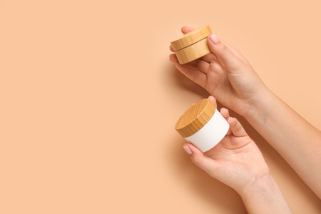 Female hands with jars of cosmetic products on color backgroundの写真素材