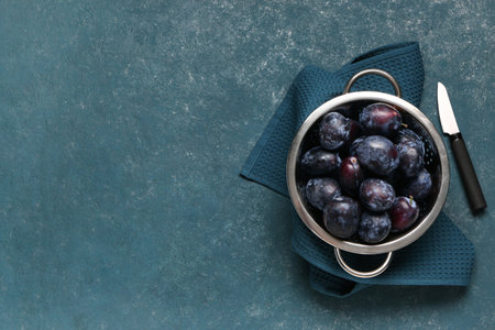 Colander with fresh plums on green backgroundの写真素材