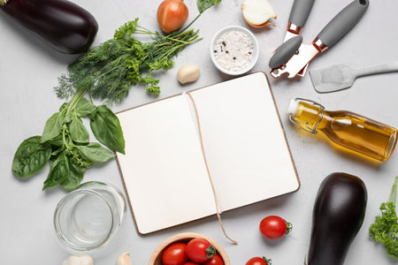 Composition with blank recipe book, fresh herbs, spices and vegetables on light backgroundの写真素材