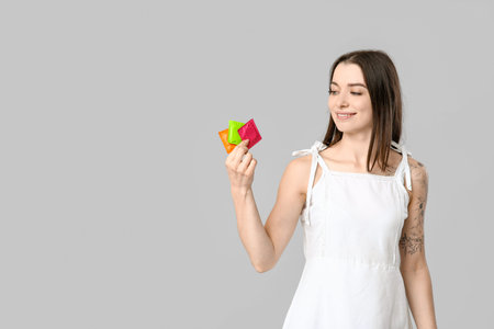 Beautiful young woman with condoms on gray background. AID awareness conceptの写真素材