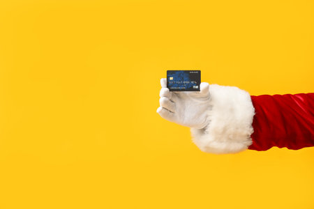 Santa Claus with credit card on yellow backgroundの写真素材