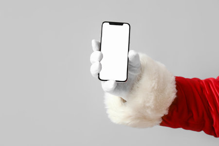 Santa Claus holding mobile phone with blank screen on gray backgroundの写真素材