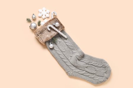 Christmas sock with fir branches and beautiful decorations on beige background