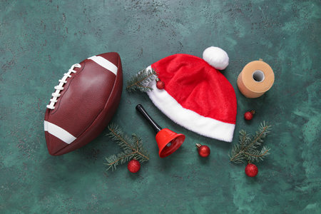 Rugby ball with Santa hat, fir branches and Christmas bell on green backgroundの写真素材