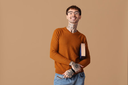 Happy young man holding book on brown backgroundの写真素材