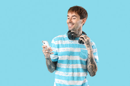 Happy young man with headphones and mobile phone on blue backgroundの写真素材