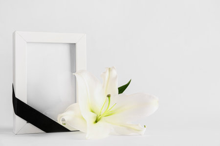 White lily and photo frame with black ribbon on white backgroundの写真素材