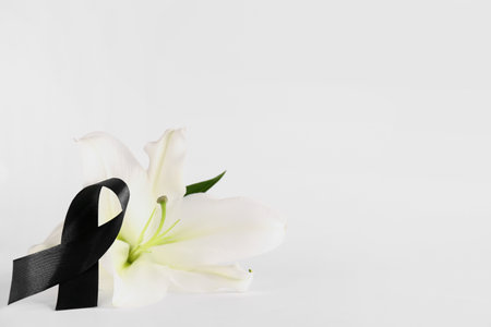 Black ribbon and lily flower on white backgroundの写真素材