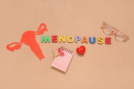 Word MENOPAUSE with paper uterus, calendar, flower and eyeglasses on beige backgroundの写真素材