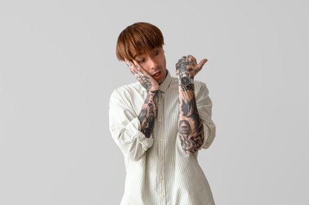Afraid young tattooed man on gray backgroundの写真素材