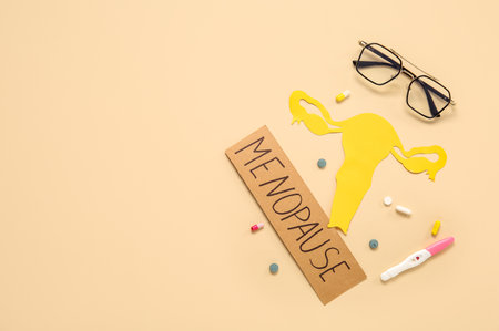 Word MENOPAUSE with paper uterus, pills, pregnancy test and eyeglasses on beige backgroundの写真素材