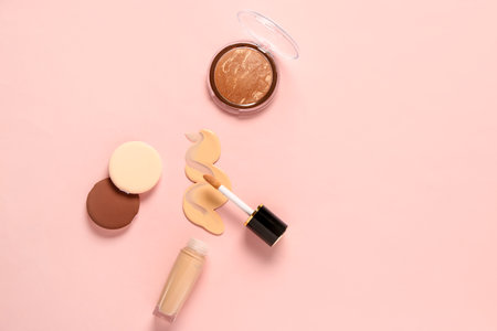 Bottle of makeup foundation with sample, highlighter and sponges on pink backgroundの写真素材