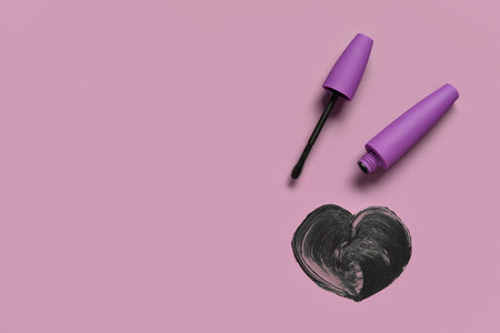 Heart made of black mascara and purple tube on color backgroundの写真素材