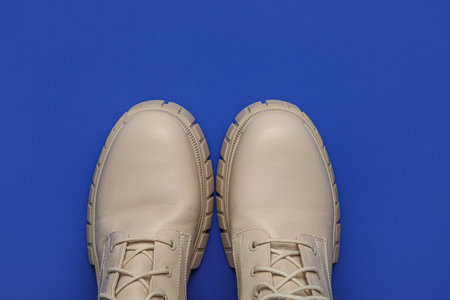 Stylish beige leather boots on blue backgroundの写真素材