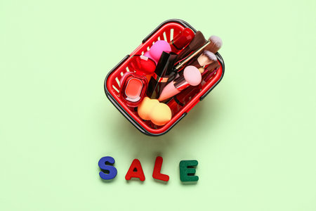 Shopping basket with makeup cosmetics and text SALE on green backgroundの写真素材