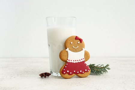 Tasty Christmas cookie with glass of milk on table against white backgroundの写真素材