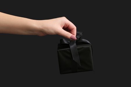 Female hand with gift box on dark background. Black Fridayの写真素材