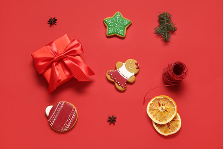Tasty Christmas cookies with gift box and decor on red backgroundの写真素材