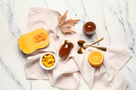 Jars of sweet pumpkin jam with orange and autumn leaf on white backgroundの写真素材
