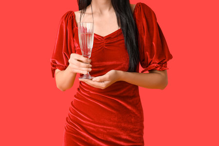 Beautiful young woman with glass of champagne on red background, closeupの写真素材