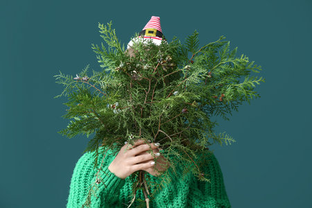 Woman holding beautiful fir tree branches on green background