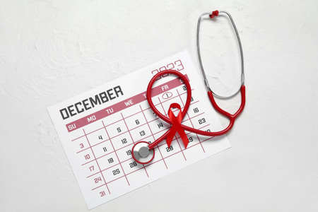 Red ribbon with stethoscope and calendar on white grunge background. AIDS Day concept