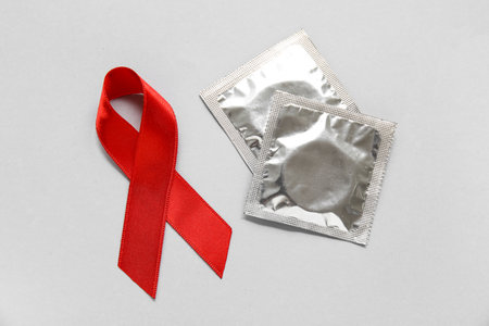 Red ribbon with condoms on light background. AIDS Day conceptの写真素材
