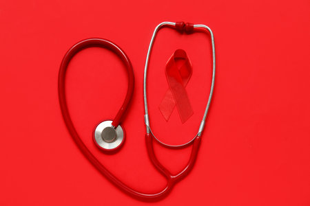 Red ribbon with stethoscope on color background. AIDS Day conceptの写真素材