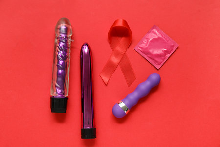 Red ribbon with sex toys and condom on color background. AIDS Day conceptの写真素材