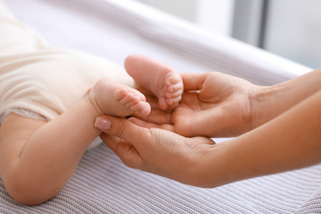 Mother massaging her baby's feet at home, closeupの写真素材