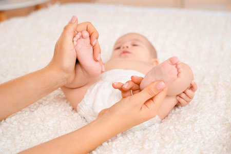Mother massaging her baby's feet in bedroom, closeupの写真素材