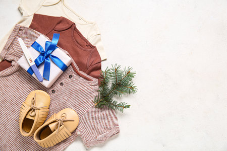 Composition with stylish baby clothes, pregnancy test and Christmas gift on light backgroundの写真素材