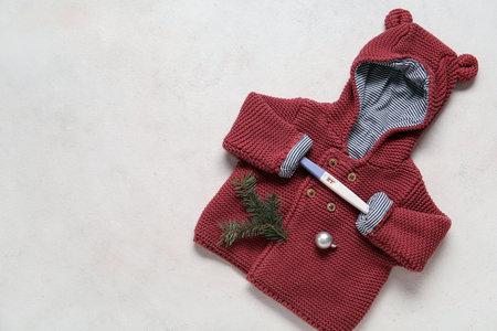Stylish baby clothes, positive pregnancy test and fir branch on light backgroundの写真素材