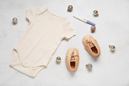 Composition with baby clothes, pregnancy test and Christmas balls on light backgroundの写真素材