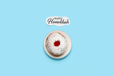 Tasty donut with jam and text HAPPY HANUKKAH on blue backgroundの写真素材