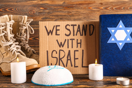 Text WE STAND WITH ISRAEL, Torah, Jewish hat, military boots and candles on wooden tableの写真素材
