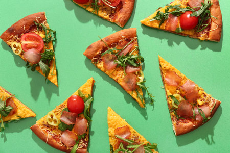 Pieces of delicious pizza with tomatoes and arugula on green background
