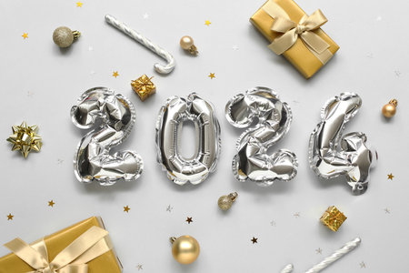 Composition with figure 2024 made of silver balloons, Christmas gifts and decorations on light backgroundの写真素材