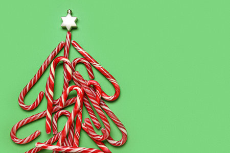 Christmas tree made of candy canes on green background