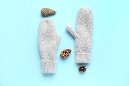 Pair of warm knitted mittens with pine cones on blue backgroundの写真素材