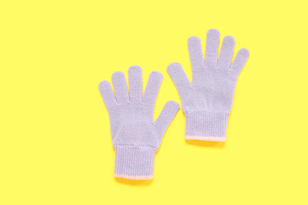 Pair of warm gloves on yellow background