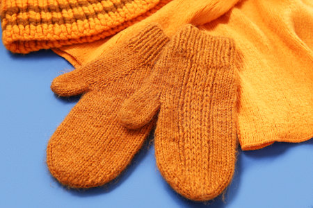 Knitted warm mittens and scarf on blue background, closeupの写真素材