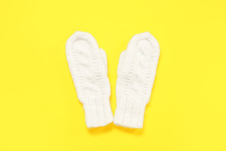Pair of stylish knitted mittens on yellow backgroundの写真素材