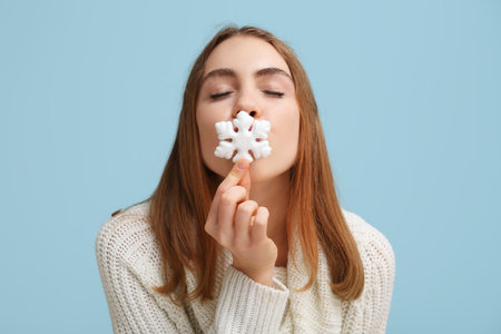 Beautiful young woman with decorative snowflake on blue backgroundの写真素材